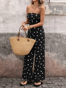 Détail d'une combinaison bustier à pois avec un sac en paille tissé et bijoux dorés