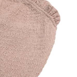 Detail of dusty rose smocked fabric with ruffle edge on a wide leg jumpsuit