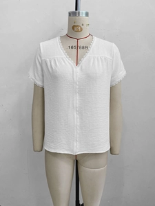 Detail of V-neck white blouse featuring delicate lace trim and subtle crinkle texture fabric