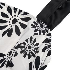Detail shot of black satin straps and daisy print on white lightweight fabric