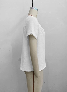 Detail of white textured top with delicate lace trim on the sleeve cuff and soft fabric