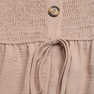 Detail of ruched bodice with tortoise button and drawstring on mauve wide-leg jumpsuit