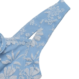 Close-up of light blue fabric featuring white floral jacquard texture and pattern