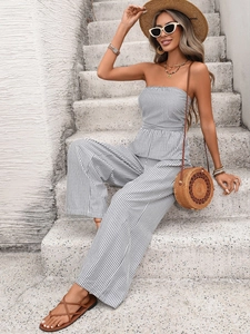 Chic strapless striped jumpsuit with wide-leg cut shown in a relaxed outdoor resort setting