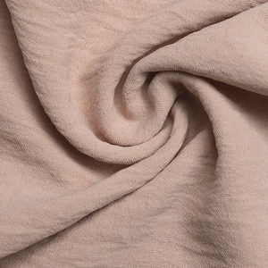 Detailed texture of dusty pink crepe fabric with soft draping and pleated layers
