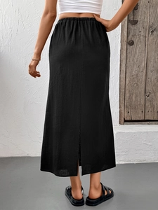 Detail view showing back slit and elastic high waist of black cotton maxi skirt