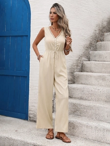 Close-up of beige textured jumpsuit featuring lace V-neck and button details