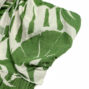 Detailed macro shot of tropical leaf print and textured linen fabric stitching on a romper