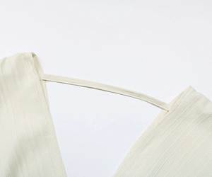 Makro-Detail des V-Ausschnitts mit Rippenmuster und feinem Riemen in Elfenbein