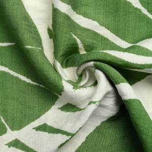 Close-up of green abstract leaf print on textured cotton linen fabric with soft folds