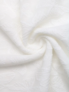 Gros plan sur un tissu en maille jacquard blanc montrant une texture douce et fine