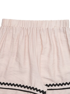 Détail du short de sport rose à taille haute avec bordure ondulée ric-rac noire sur les bords