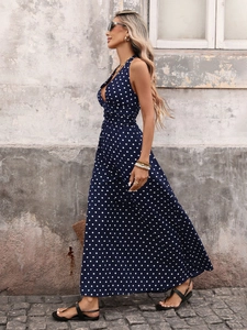 Detail of navy blue polka dot halter dress featuring a deep V-neck and flowing skirt