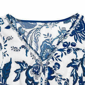Detail of elegant V-neckline with blue trim and floral print on white summer dress