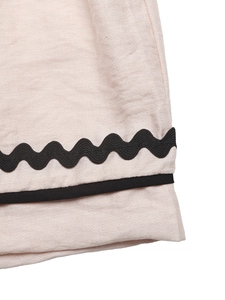 Gros plan détaillé du tissu rose texturé avec bordure noire en forme de vaguelettes