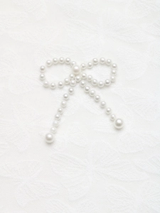 Détail d'un accessoire nœud papillon en perles élégantes sur dentelle blanche