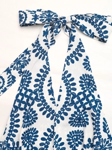 Detail of blue floral halter neck tie on white summer dress with botanical leaf pattern