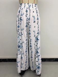 Detail of tiered wide-leg trousers with smocked waist and blue floral bohemian print