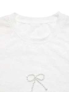 Détail du tissu jacquard papillon blanc avec un nœud en perles sur l'encolure