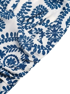 Detailed close-up of blue botanical print on lightweight white woven cotton fabric