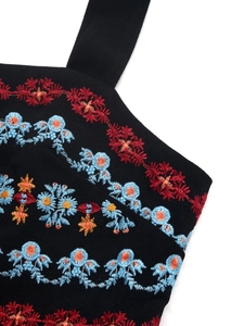Close-up of colorful ethnic floral embroidery on black sleeveless summer romper fabric