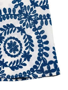 Detailed view of the blue floral print and embroidery on the white summer dress hem