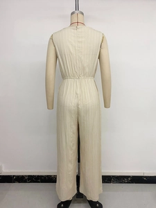 Back view of beige sleeveless jumpsuit featuring textured pleats and a concealed zipper