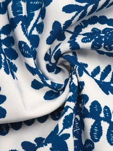 Close-up of the white textile fabric with deep blue leaf patterns and soft drape texture