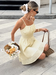 Detail of light yellow mini dress with thin straps, ruched bodice and ruffled hemline