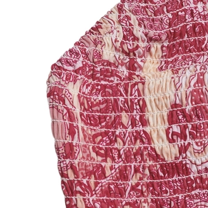 Gros plan sur le tissu élastique smocké d'un ensemble avec motifs bohèmes rouges