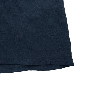 Detailed close-up of dark blue fabric featuring vertical pleated texture and fine stitching