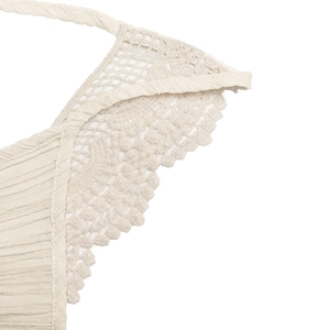 Detailed view of beige pleated fabric with delicate crochet lace trim and deep V-neckline