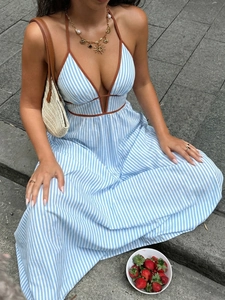 Détail d'une robe longue rayée bleue à col licou avec bordure et sac en paille