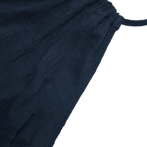 Detail of navy blue crinkle fabric featuring smocked elastic waist and thin shoulder straps