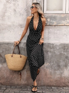 Detail of a black polka dot maxi dress featuring a deep V-neck and halter neck design