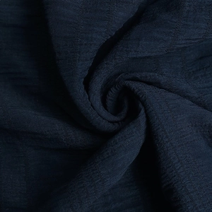 Macro detail of navy blue dress fabric with subtle plaid texture and soft draping effect