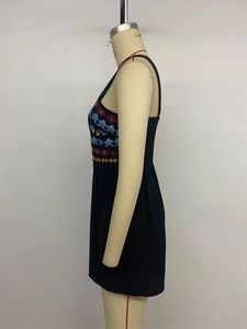 Detail of colorful floral embroidery and smocked back on black sleeveless romper dress