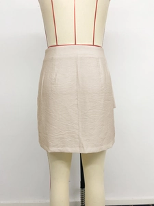 Detailed view of beige high-waist mini skirt texture and waist pleat craftsmanship