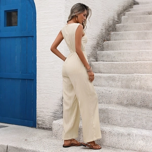 Beige sleeveless wide-leg jumpsuit with textured fabric shown on a model in a resort setting