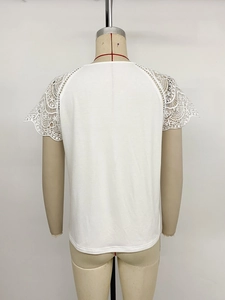 Detailed macro view of white short sleeve top with intricate hollow lace floral stitching