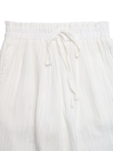 Detail of white trousers showing the elastic ruffle waistband with adjustable drawstring