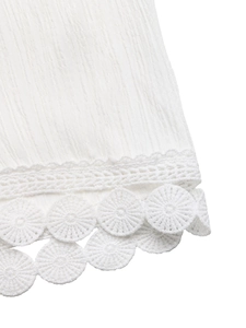 Close-up of white pleated trousers with delicate circular crochet lace hem detail