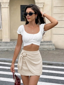 Detail of high-waist wrap skirt featuring a large golden metal ring buckle decoration