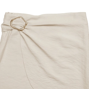 Detail of high waist skirt featuring elegant irregular gold metal buckle and draped wrap fabric