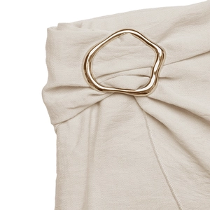 Detailed close-up of an apricot bodycon skirt featuring a shiny gold irregular metal buckle