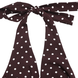 Close-up of brown halter neck dress with white polka dots and elegant knot detail