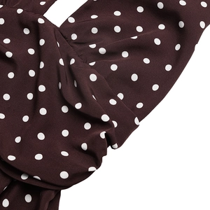 Detailed view of deep brown polka dot dress with elegant V-neckline and draped fabric