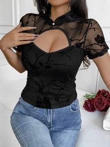 Detail of black mesh top featuring a high neck with pearl buttons and heart cutout