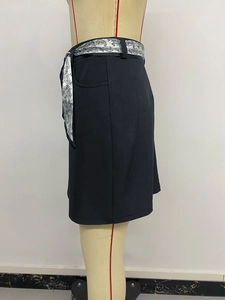 Dettaglio gonna attillata scura con cintura in raso a motivi paisley bianchi su un manichino