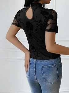 Detail of sheer black mesh top featuring floral velvet flocking and teardrop back closure